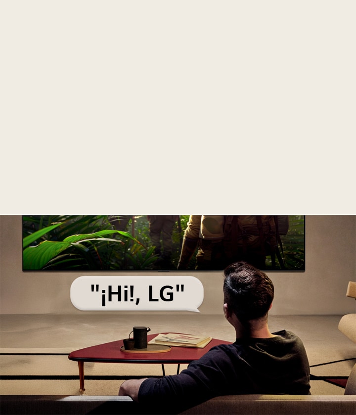 El LG OLED evo AI G6 con Reconocimiento de Voz de campo lejano se activa a través de un comando de voz cuando una persona sentada en una habitación dice "¡Hi!, LG" hacia el televisor, lo que indica una interacción de voz de manos libres dentro de la interfaz del televisor.